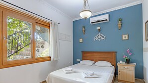 Une chambre bien rangée, avec un lit, une table de chevet et une fenêtre avec des rideaux.