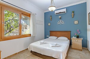 Un dormitorio ordenado con cama, mesita de noche y ventana con cortinas.