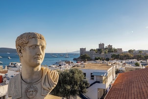 Una estatua con vista a un pueblo costero y un castillo al fondo.