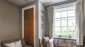 Une pièce chaleureuse avec un canapé gris, une porte en bois et une fenêtre avec des rideaux.