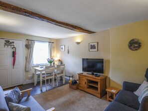 Ein Wohnzimmer mit Fernseher, Sofa und Essbereich mit Tisch und Stühlen.