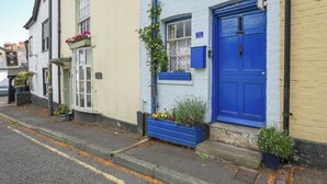 Une rangée de bâtiments traditionnels, chacun doté d’une porte bleue et d’une enseigne indiquant qu’il s’agit d’une maison de campagne.