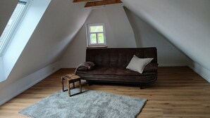 A loft-style room with a brown leather sofa, a small wooden table, and a gray rug. - Lovingly renovated East Frisian brick house "Huus up Hook" (Krummhörn)
