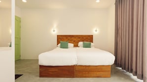 A double bed with a wooden headboard, two green pillows, and a light-colored carpet. - Azul Retreat (Dhigurah)