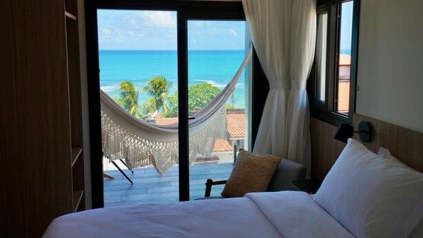 Ein Schlafzimmer mit Bett, Meerblick und einer Hängematte.