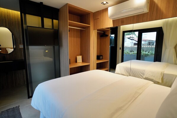 A hotel room with two beds, a built-in wardrobe, a mirror, and a view of the outside.
