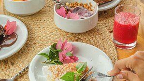 Ein Tisch mit verschiedenen Speisen und Getränken, darunter ein grüner Smoothie, ein rotes Getränk und Teller mit Essen.