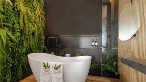 Ein modernes Badezimmer mit freistehender Badewanne, einer Duschkabine aus Glas und einer vertikalen Grünwand.
