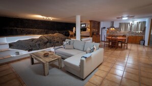 Un salon avec un canapé, une table basse et un mur en pierre.