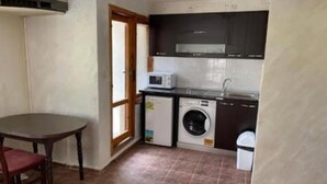 A compact kitchen with a washing machine, a microwave, and a sink.