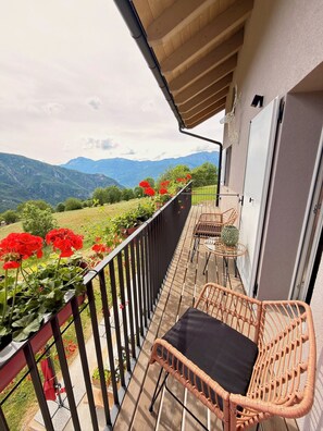 A balcony with wicker chairs, a table, and a view of mountains.