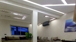 A spacious lobby with a modern design, featuring a large sofa, a wooden reception desk, and a potted plant. - Charming apartment in wonderful Fes with WiFi, AC (Fes)