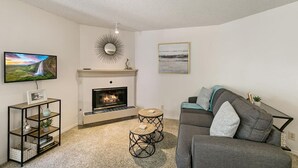A living room with a fireplace, a television, a sofa, and a coffee table. - DTC Apartment! Perfect for Your Extended Stay! (Greenwood Village)