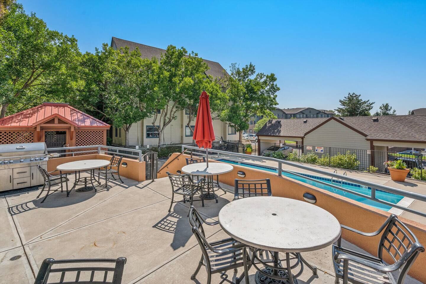 Un patio exterior con piscina, parrilla y zona de estar.