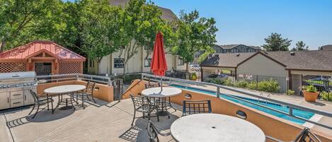 Un patio exterior con piscina, parrilla y zona de estar.