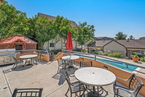 Eine Außenpatio mit Pool, Grill und Sitzgelegenheit.