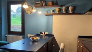 A kitchen with a window, a bowl of fruit, a clock, and a shelf with decorative items. - Charming 1 bedroom & sofa bed in a unique and quaint part of Florence. (Firenze)