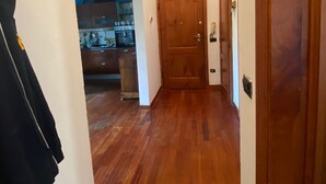 A hallway with wooden flooring, a coat rack, and a door leading to a kitchen area. - Charming 1 bedroom & sofa bed in a unique and quaint part of Florence. (Firenze)