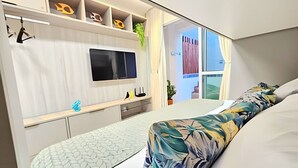 Une chambre à coucher moderne avec un lit, une télévision, un bureau et une fenêtre.