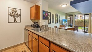 A kitchen with granite countertops, wooden cabinets, and a built-in dishwasher. - Charming Tropical Kihei Gardens 2-Bed Suite (Kihei)