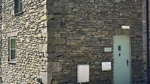 A stone building with a green door, a small window, and a sign indicating it's a cottage.