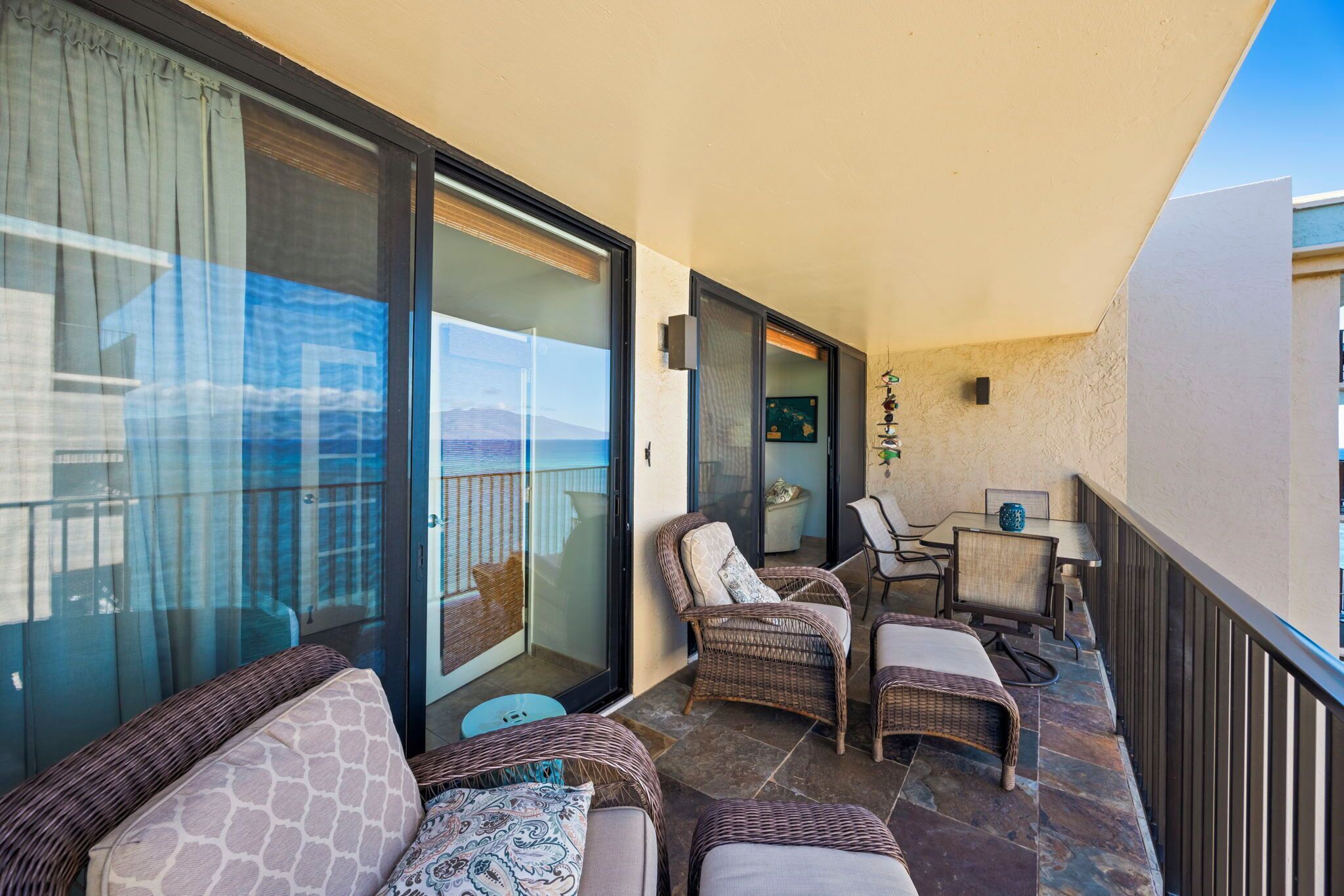 A balcony with wicker furniture, a glass door leading to a balcony, and a small table with chairs.