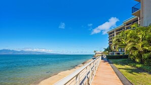 A coastal walkway with a clear view of the sea and mountains in the background.