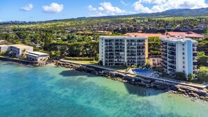 A coastal hotel with multiple floors, a pool, and a view of the surrounding residential area.