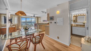 A modern kitchen with a glass dining table, wooden chairs, and a ceiling fan. - MK404 - Sleep at the Ocean and Watch Sunsets 3-Bed Suite (Lahaina)