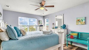 Ein Schlafzimmer mit Bett, Deckenventilator, Kommode, Bank und Fenster mit Jalousien.