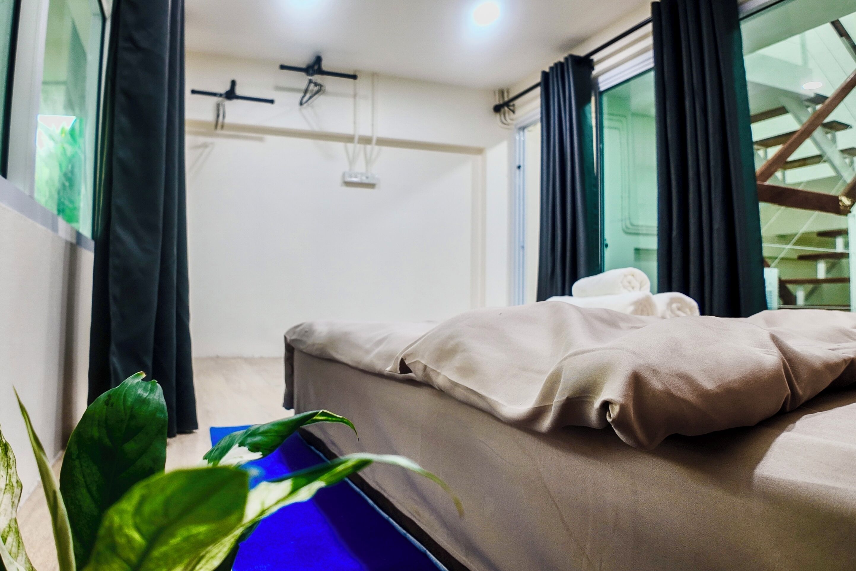 Une chambre d’hôtel avec un lit, une chaise bleue et une plante en pot.