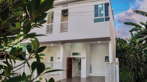 Un edificio de dos pisos con puertas numeradas, un vestíbulo cubierto y fachada blanca.