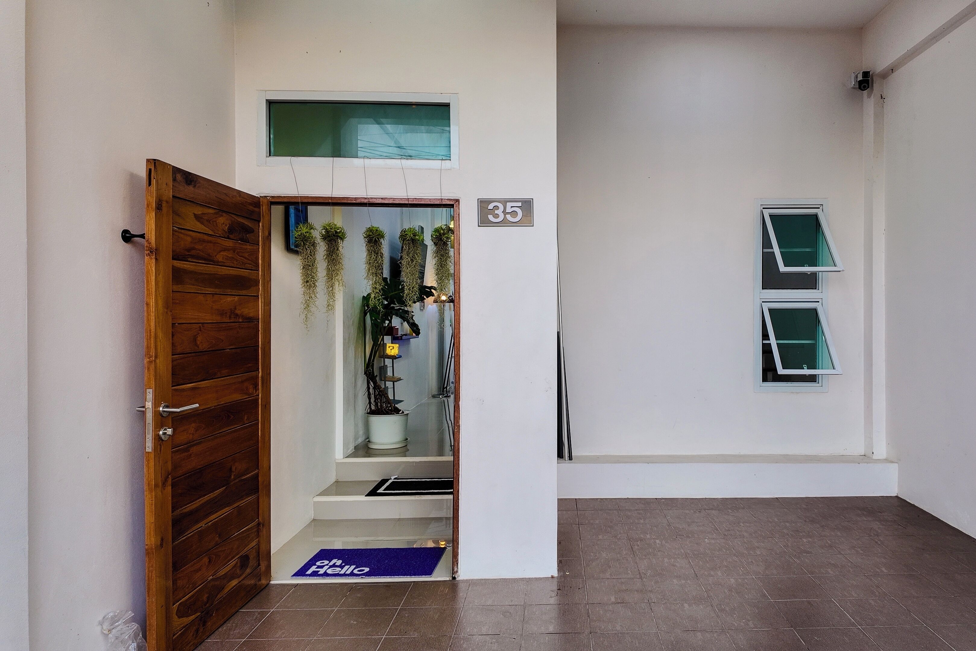 A hallway with a wooden door, a small window, and a number '35' on the wall.