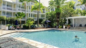 A pool area with lounge chairs, palm trees, and a multi-story building with balconies. - Hyatt Sunset Harbor. Available Oct 19 to 26.   Studio. 3 night minimum rental.   (Key West)