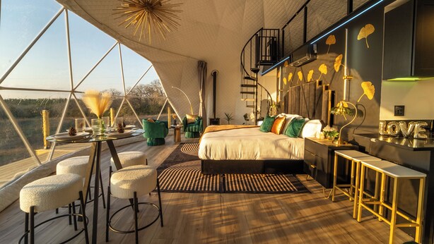 A spacious bedroom with a large bed, a desk, and a view of the outdoors. - Luxurious Stargazer Dome Retreat in Stunning Nature w/Hot Tub and Sauna! (Smithville)