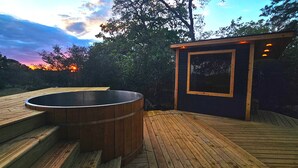 A hot tub on a wooden deck with a view of the sunset and trees. - Luxurious Stargazer Dome Retreat in Stunning Nature w/Hot Tub and Sauna! (Smithville)