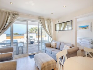 Et moderne værelse med sofa, spisebord og balkon med udsigt.