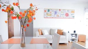 A dining area with a table and chairs, a vase with flowers, and a white sofa in the background. - Beautiful apartment in Palermo Soho (Buenos Aires)