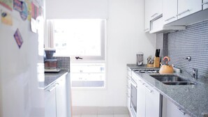 A modern kitchen with white cabinets, a granite countertop, and a window providing natural light. - Beautiful apartment in Palermo Soho (Buenos Aires)