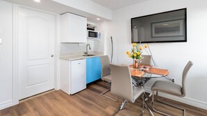 A compact kitchen with white cabinets, a blue dishwasher, and a microwave above the sink. There is a dining table with chairs and a vase of flowers. - Luxury retreat with Amazing Views, Great Location with free parking! (Halifax)