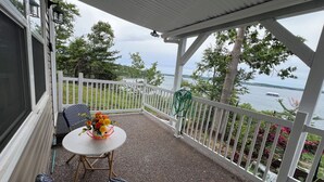 A covered patio with a white railing, a table with chairs, and a view of the water. - Luxury retreat with Amazing Views, Great Location with free parking! (Halifax)
