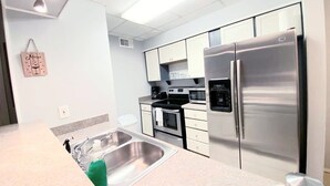 A modern kitchen with stainless steel appliances, a double sink, and white cabinetry.