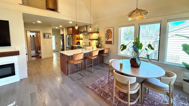 Een ruime keuken met een centraal eiland, houten vloeren en een eethoek met een ronde tafel en stoelen.