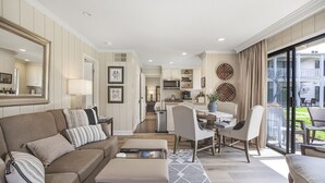A spacious living room with a sofa, ottoman, and a dining area with a table and chairs.