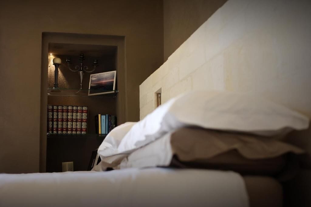 Un dormitorio con una cama, una mesita de noche, una lámpara y una estantería.