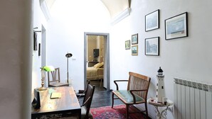 Un comedor con una mesa, sillas, un tapete rojo estampado, una lámpara y cuadros en la pared.