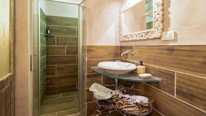 Un baño con cabina de ducha de vidrio, un lavabo con encimera de vidrio y un espejo decorativo.