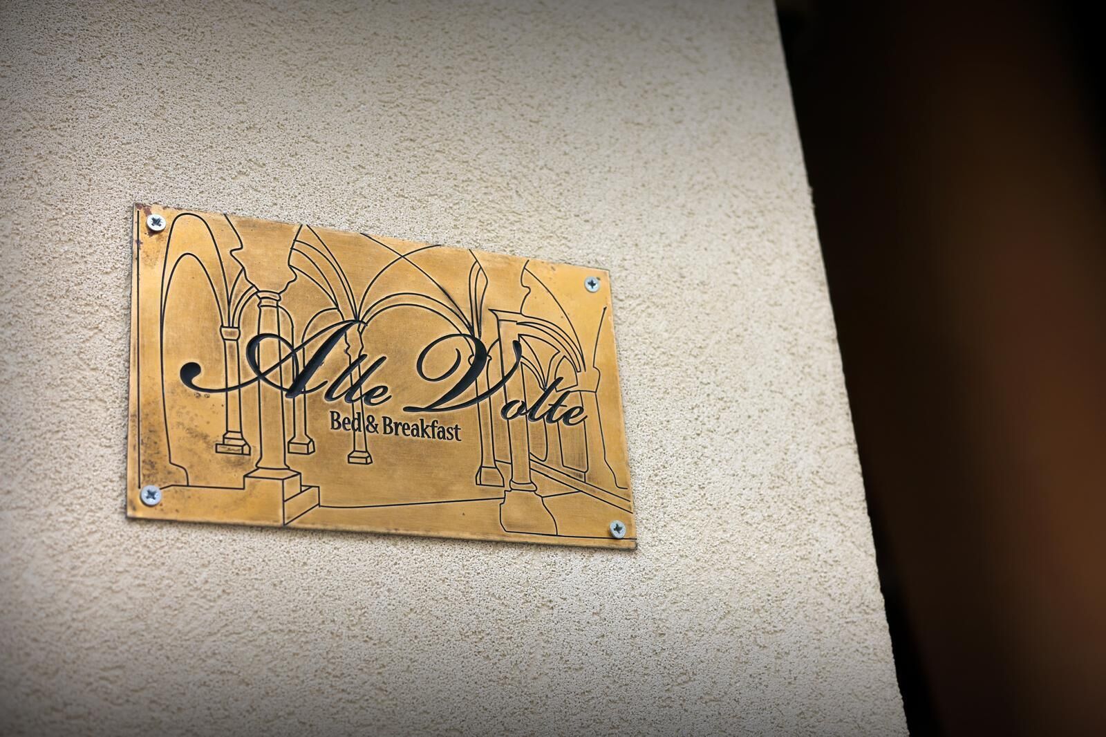 Un letrero con el texto 'Alte Dolce Bed & Breakfast' sujeto a una pared.
