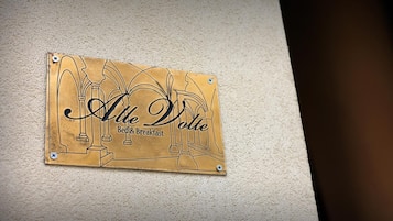 Un letrero con el texto 'Alte Dolce Bed & Breakfast' sujeto a una pared.