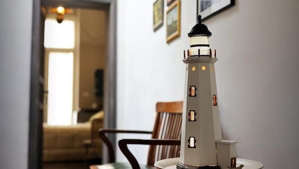 Un faro modelo sobre una mesa, con una silla y una puerta al fondo.